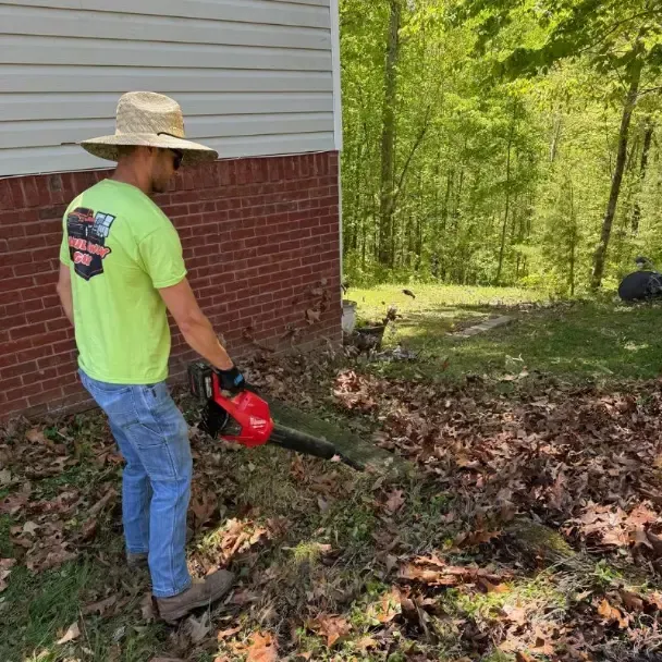 Person using leaf blower outdoors.