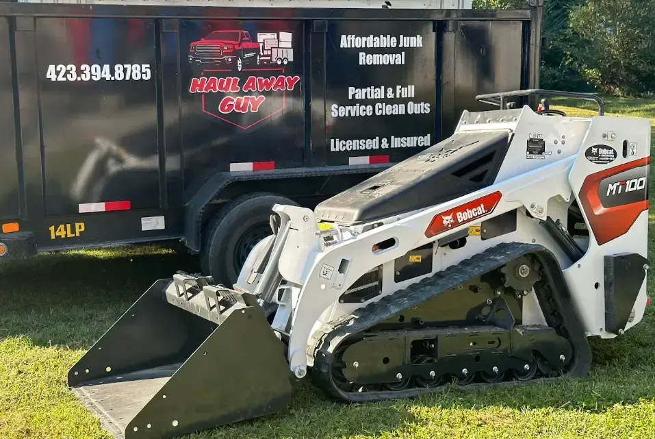 Bobcat loader beside junk removal trailer