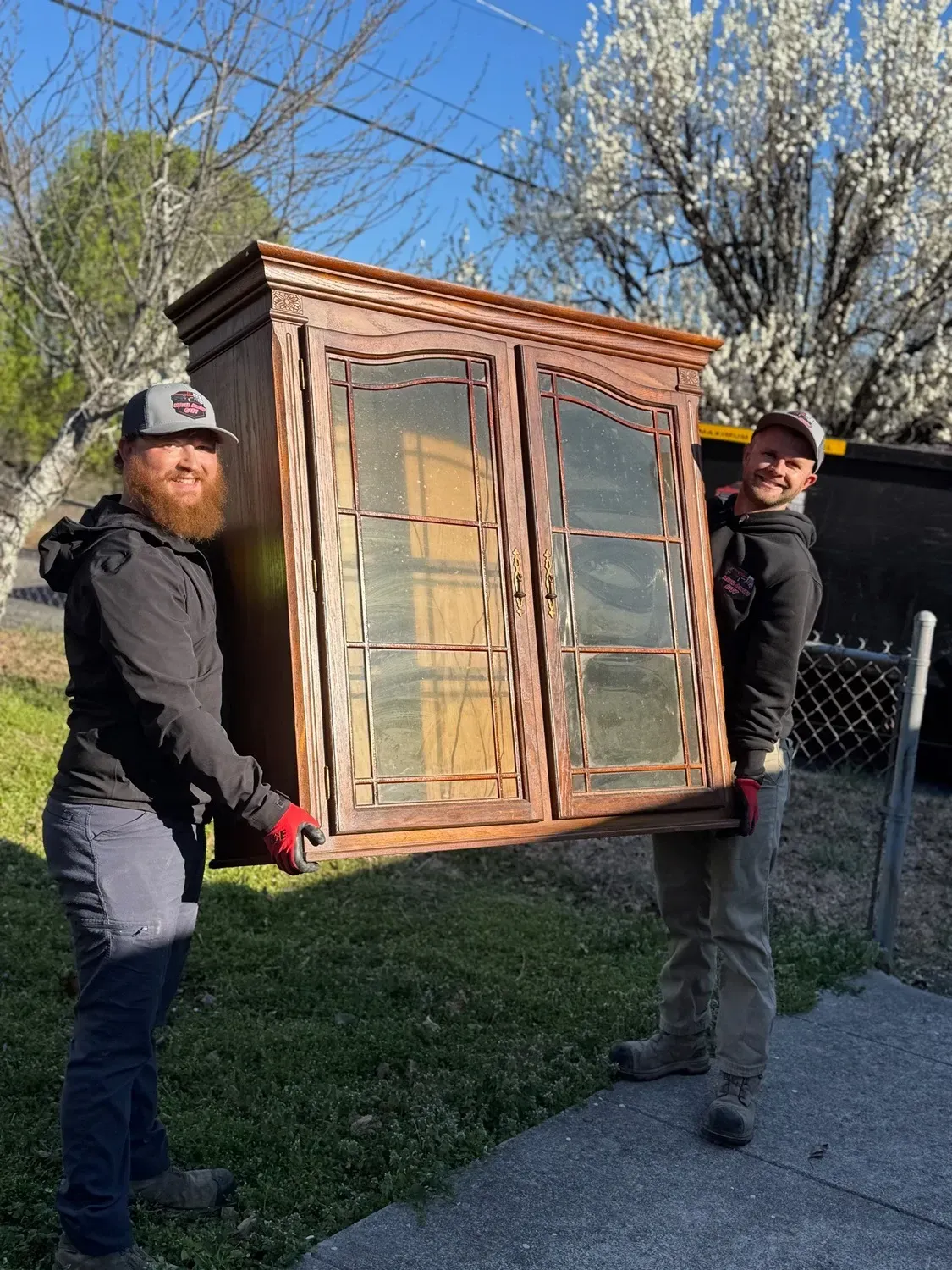 Two people lifting wooden furniture.