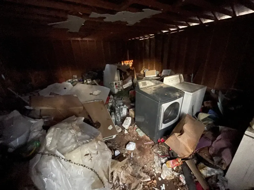 Cluttered storage area with appliances and debris