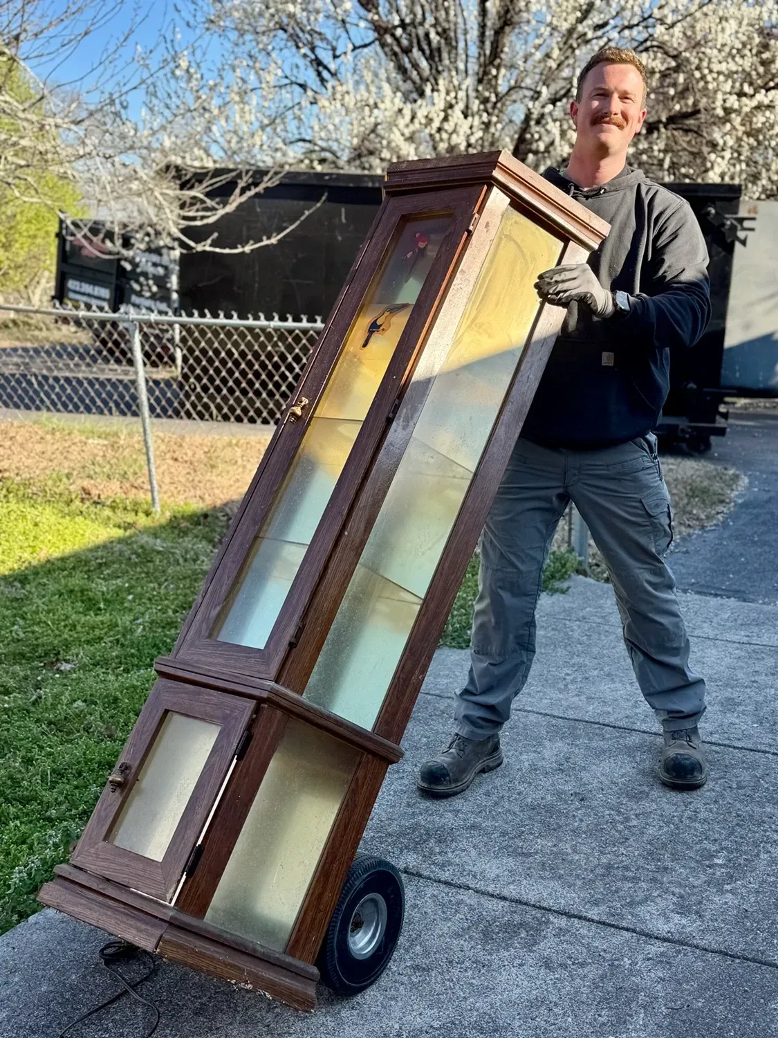 Person moving a wooden display cabinet.