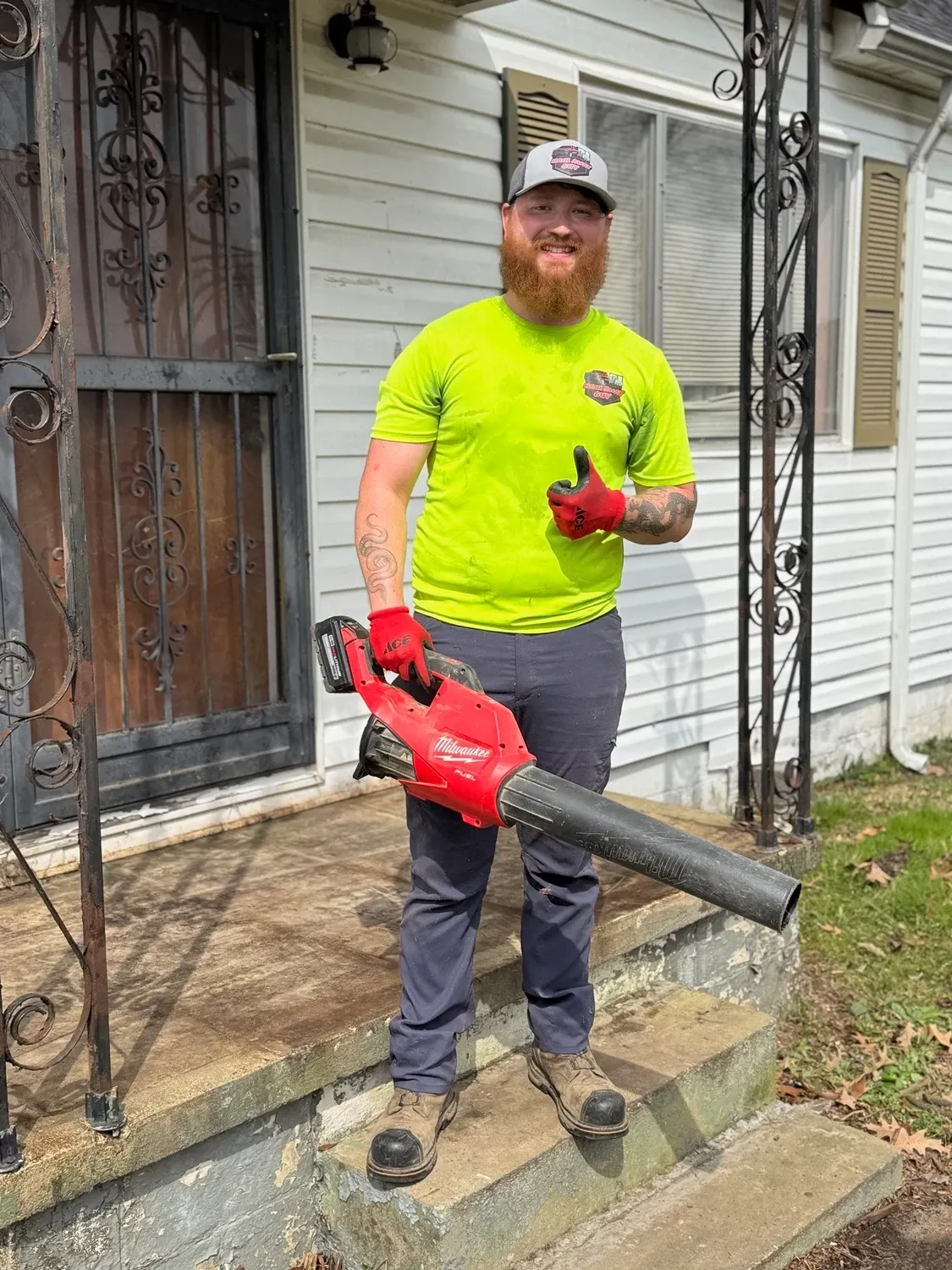 Man with leaf blower on porch.