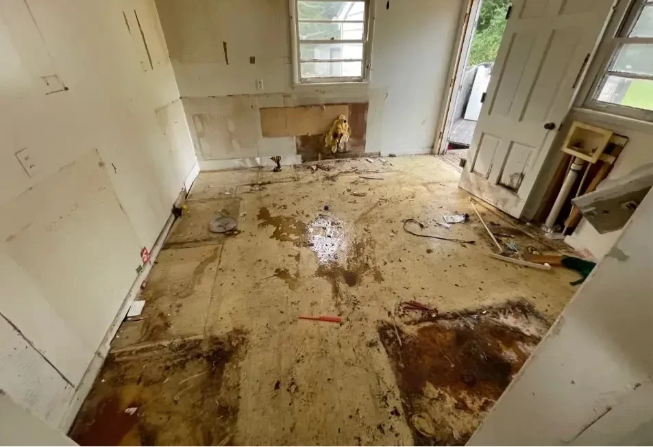 Messy, damaged room with exposed floor.